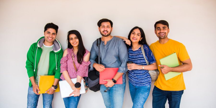 Cheerful Indian asian young group of college students or friends laughing together while sitting, standing or walking in campus